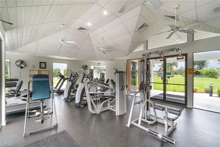 Exercise room with ceiling fan, a paneled ceiling, and vaulted ceiling