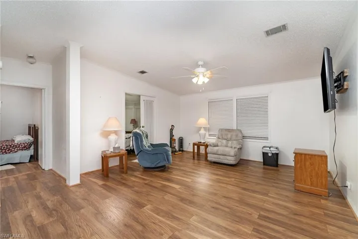Living area with hardwood / wood-style floors, a textured ceiling, and ceiling fan