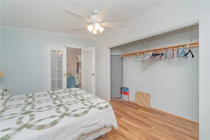 Bedroom with hardwood / wood-style floors, ornamental molding, a closet, and ceiling fan