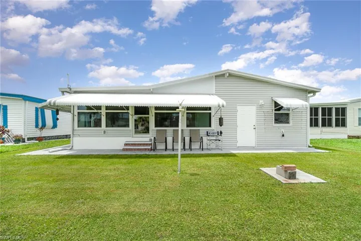 Rear view of house with a patio area and a lawn