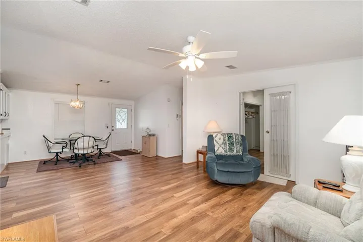 Living room featuring a textured ceiling, ceiling fan with notable chandelier, and light hardwood / wood-style floors