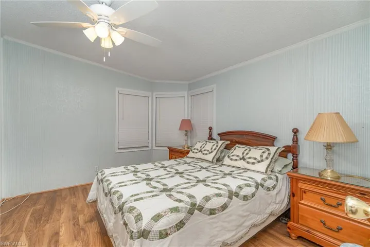Bedroom featuring ceiling fan, crown molding, and light hardwood / wood-style floors