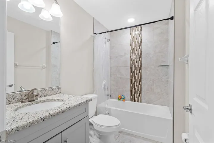 Bathroom featuring toilet, vanity, tile patterned flooring, and shower / tub combo