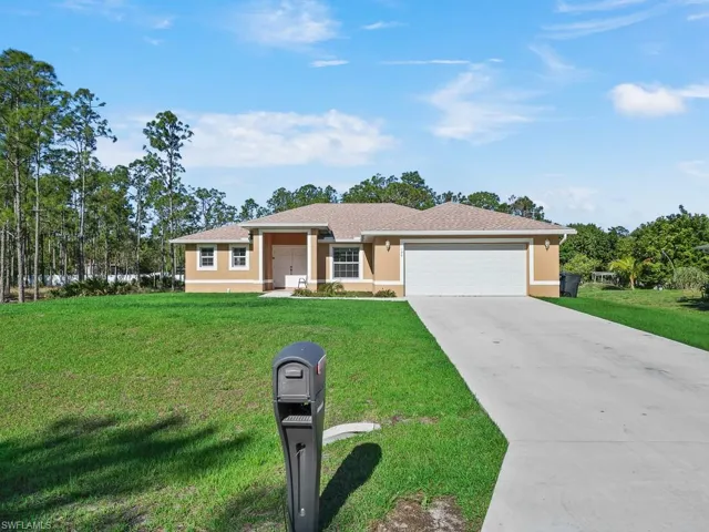Single story home with a front yard, stucco siding, an attached garage, and concrete driveway