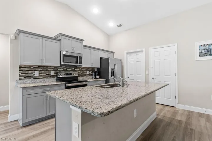 Kitchen with gray cabinetry, a sink, and stainless steel appliances
