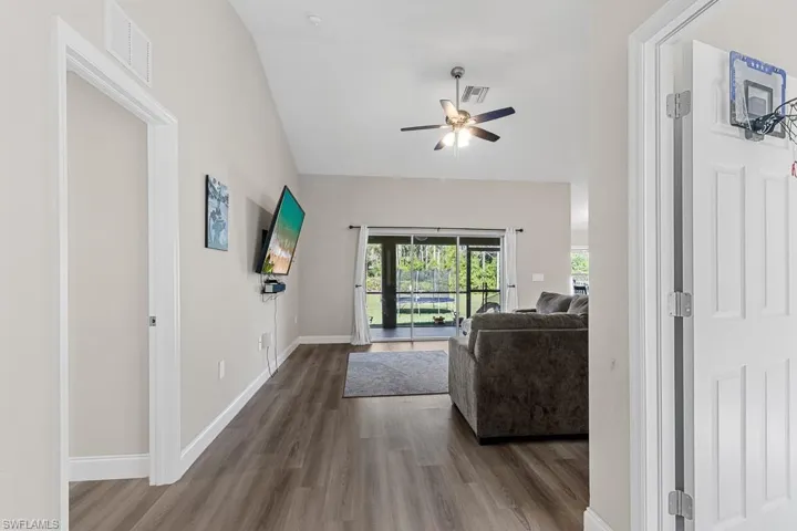 Living area featuring wood finished floors, baseboards, ceiling fan, and visible vents