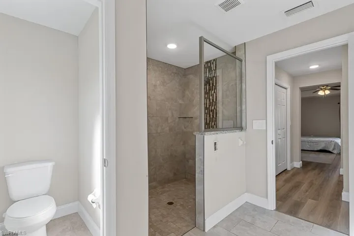 Ensuite bathroom featuring baseboards, visible vents, and a walk in shower