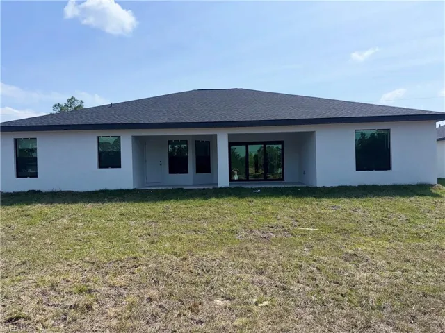 Back of house with a patio area, a lawn, and stucco siding