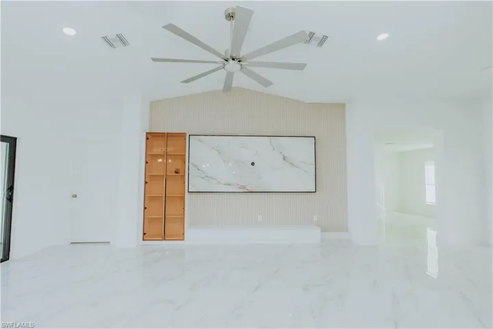 Empty room featuring light marble finish flooring, lofted ceiling, recessed lighting, and ceiling fan