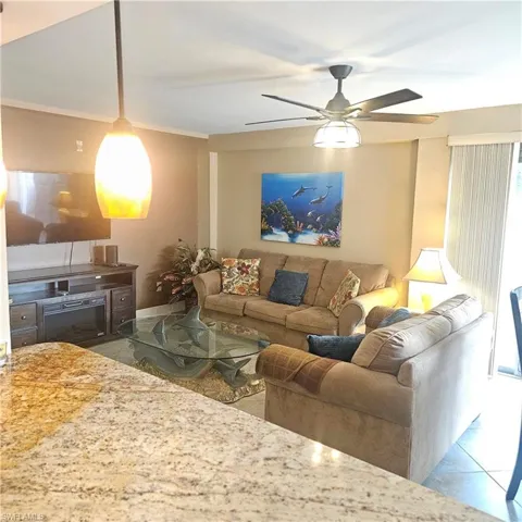 Tiled living area featuring a ceiling fan and crown molding