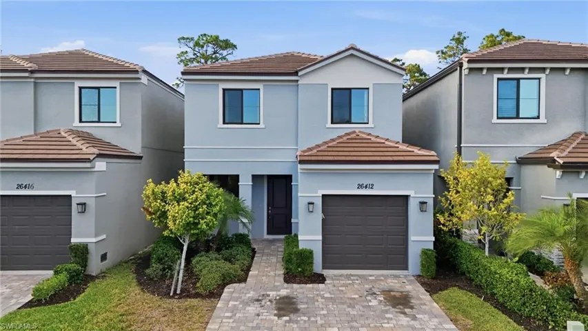 View of front of house with a tile roof, a garage, and driveway
