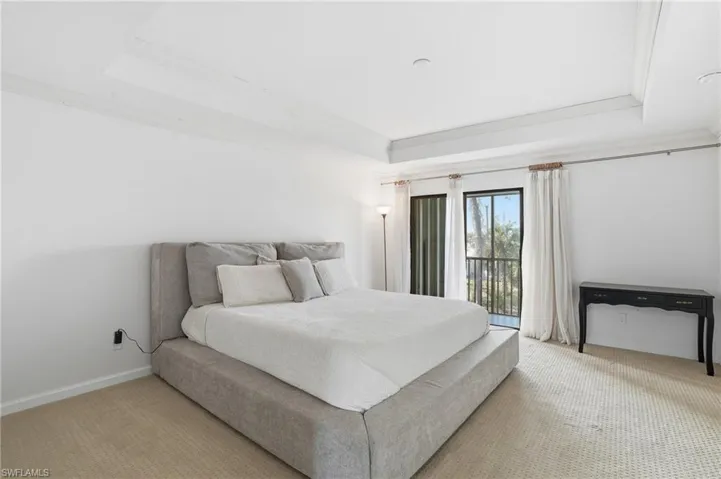 Bedroom featuring access to outside, carpet flooring, a tray ceiling, and crown molding