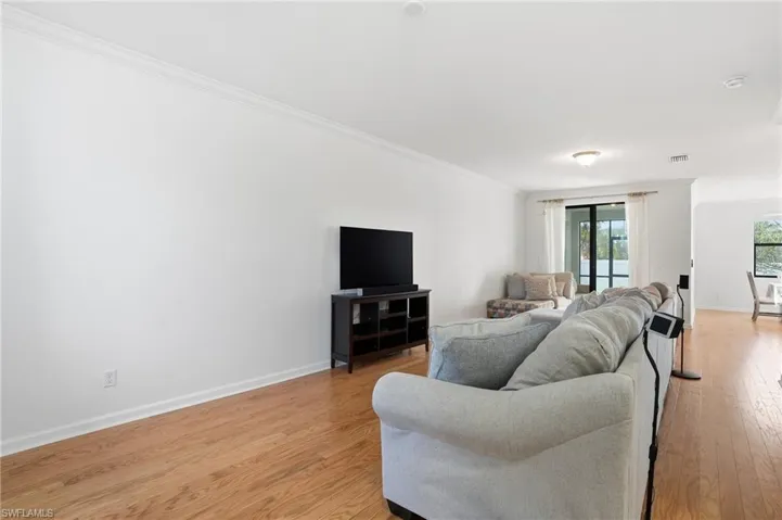 Living room with light wood-type flooring and crown molding