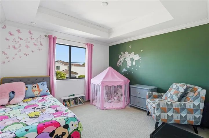 Bedroom with light carpet, ornamental molding, and a crib