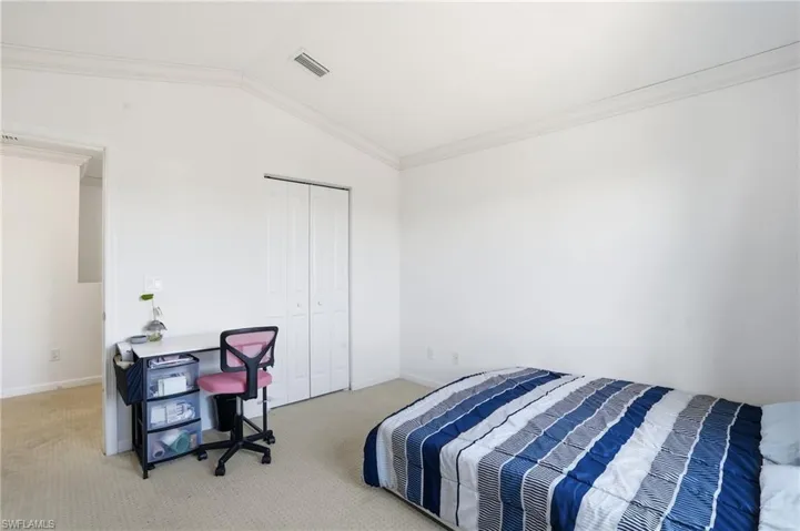 Carpeted bedroom with lofted ceiling, ornamental molding, and a closet