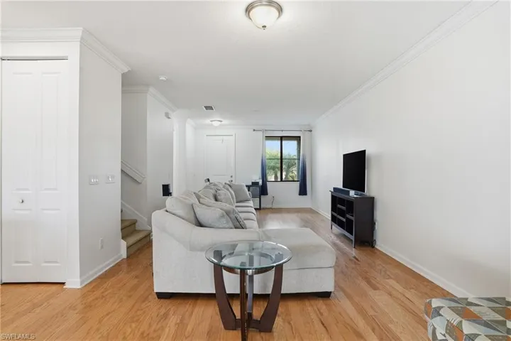 Living room with crown molding, stairway, and light wood finished floors