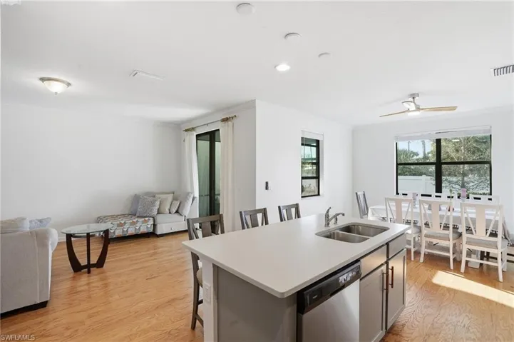 Kitchen with light countertops, an island with sink, a kitchen bar, light wood-style flooring, and dishwasher