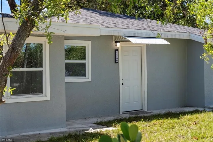 Property entrance featuring stucco siding and roof with shingles