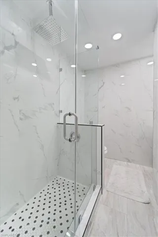Bathroom featuring toilet, recessed lighting, and a marble finish shower