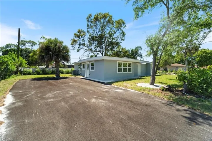 View of front of house with central AC, stucco siding, and aphalt driveway