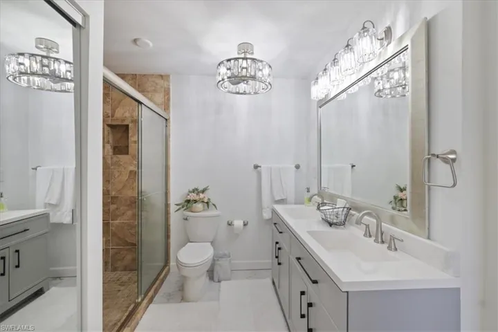 Bathroom featuring double vanity, a stall shower, and suspended lighting