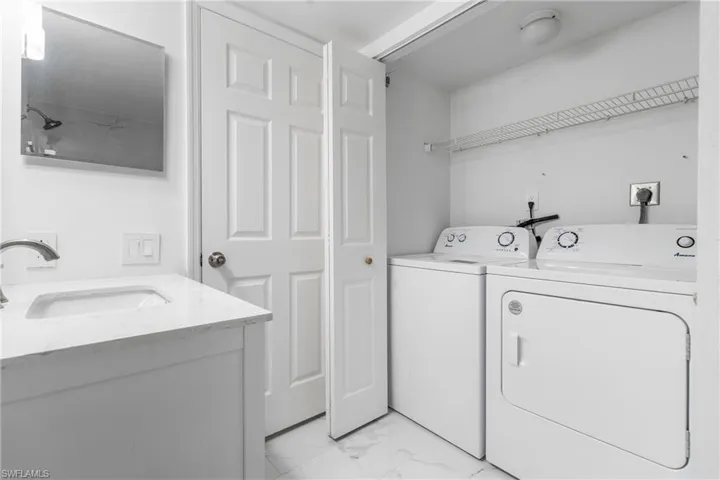 Washroom featuring light marble finish floors and washing machine and dryer