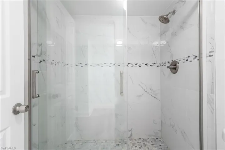 Full bath with a marble finish shower
