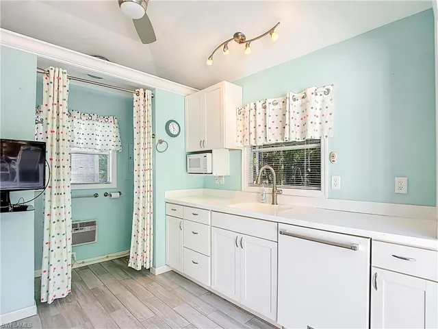 Kitchen with white cabinets, white appliances, light countertops, a ceiling fan, and lofted ceiling