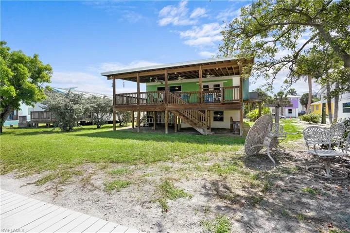 Back of house featuring a ceiling fan, a yard, stairway, and a wooden deck