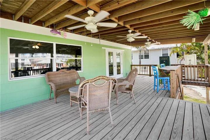 Wooden terrace with outdoor dining area, french doors, and ceiling fan