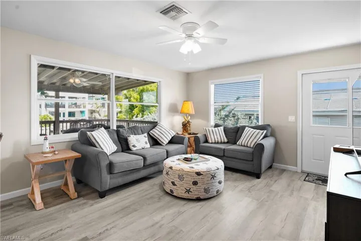 Living area featuring a ceiling fan, light wood finished floors, baseboards, and healthy amount of natural light