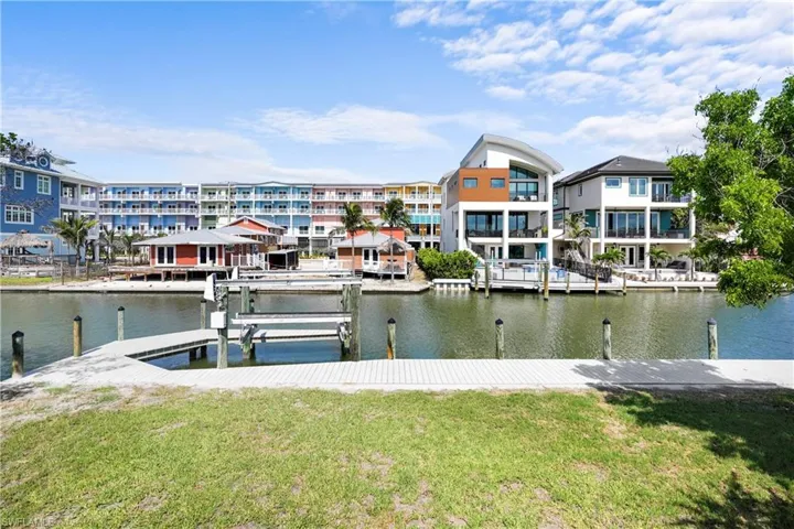 Dock with a water view, boat lift, and a lawn