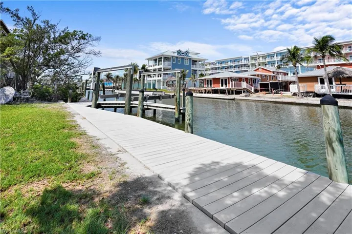 Dock with a water view, boat lift, and a lawn