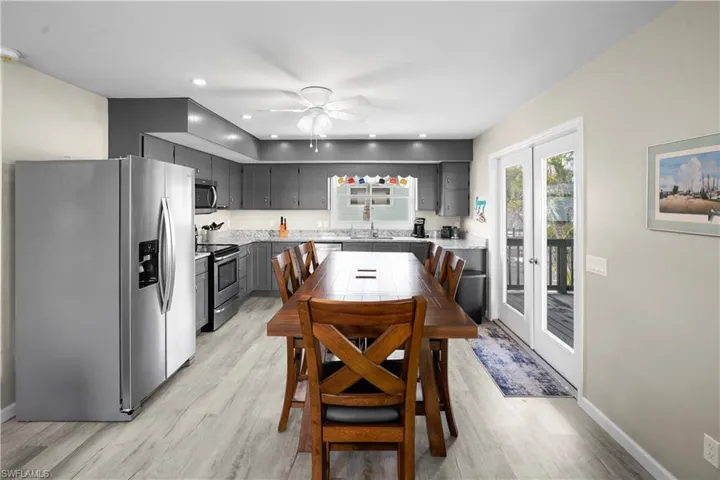 Dining area featuring French doors to the large covered deck that overlooks the canal. Sold wood shaker cabinets in a slate grey add a warm feel. The Granite counter tops and large single basin stainless steel sink make it a chef's dream. Light wood finished luxury vinal floors, recessed lighting.
