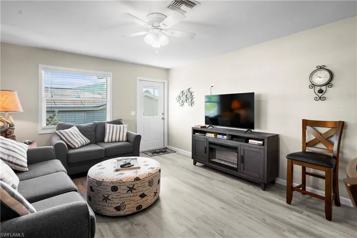 Living area with light wood finished floors, a ceiling fan, and baseboards