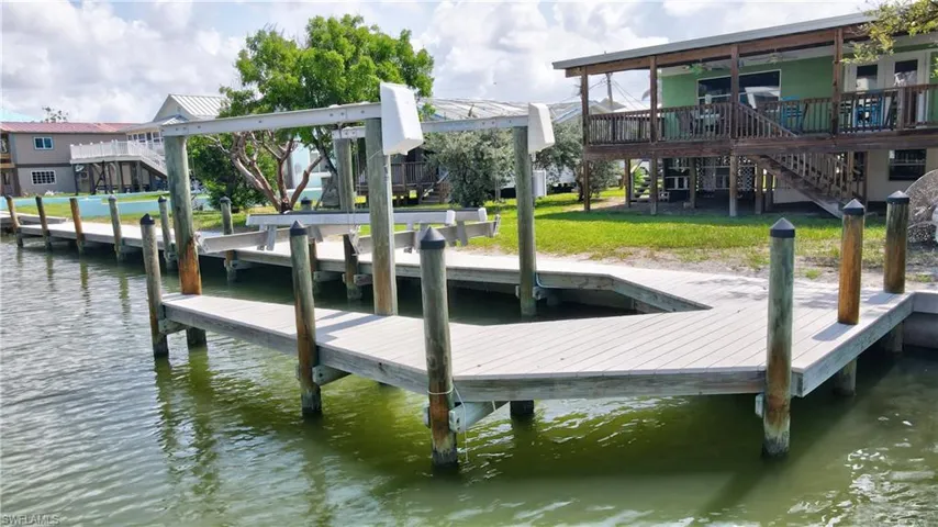 Dock area with stairway, a water view, and a lawn