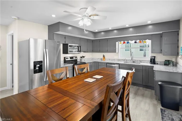 Kitchen has stainless steel appliances, solid wood gray cabinets, single basin deep sink, granite counter tops, light finished wood-type luxury vinyl flooring and french doors to the large deck overlooking the water.