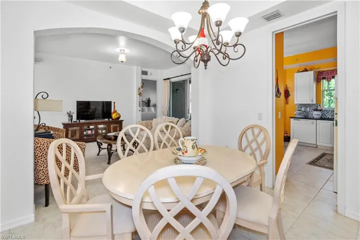 Dining space featuring arched walkways, a chandelier, and light tile patterned floors