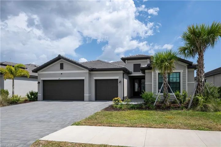 View of front of home with decorative driveway, a garage, stucco siding, a front yard, and a tile roof