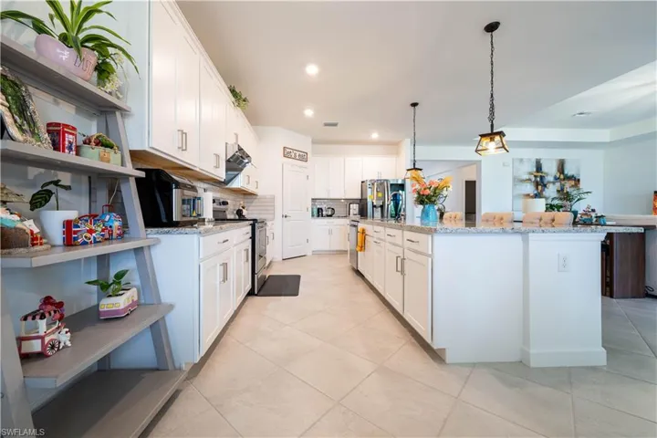Kitchen featuring open shelves, white cabinetry, stainless steel appliances, light stone countertops, and recessed lighting