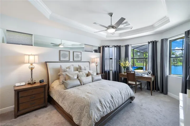 Bedroom featuring crown molding, light carpet, ceiling fan, and a raised ceiling
