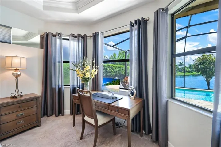 Carpeted home office featuring ornamental molding and a tray ceiling