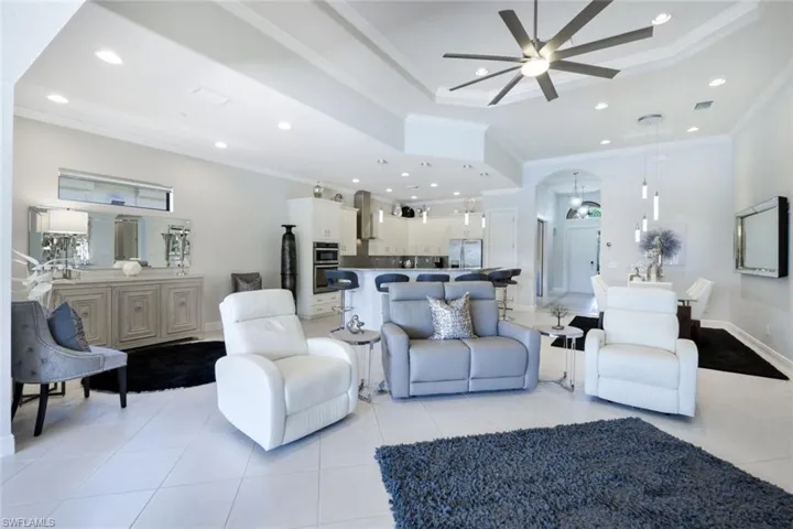 Living room featuring ornamental molding, light tile patterned floors, and ceiling fan