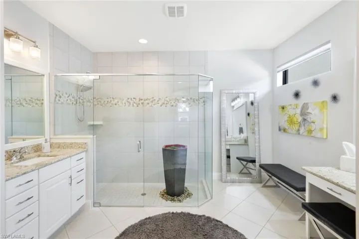 Bathroom featuring tile patterned floors, a shower with door, and vanity