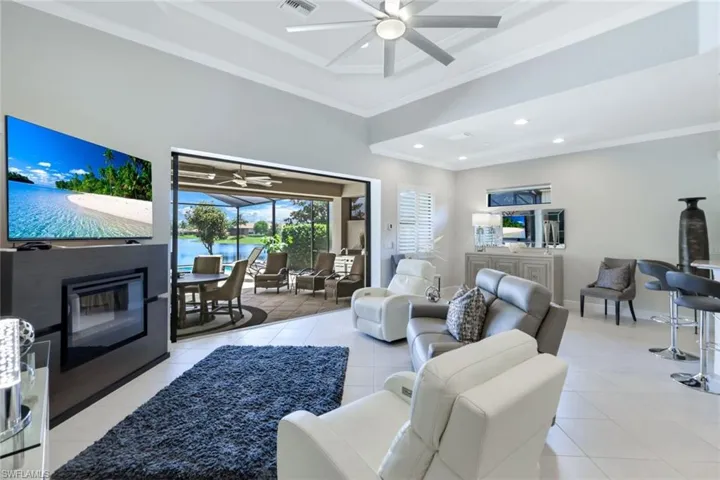 Living room with ornamental molding, light tile patterned floors, and ceiling fan