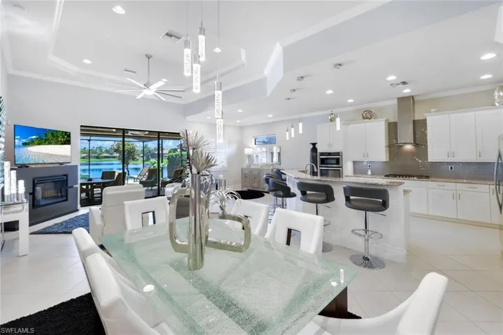 Dining area featuring crown molding, light tile patterned floors, a raised ceiling, and ceiling fan