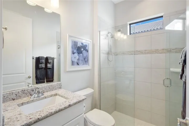 Bathroom with a shower with door, toilet, and vanity