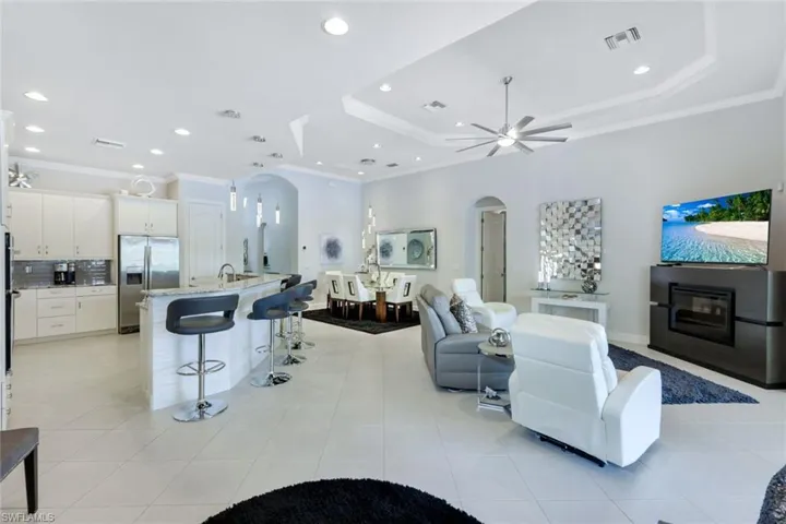 Tiled living room featuring ceiling fan, crown molding, and a tray ceiling