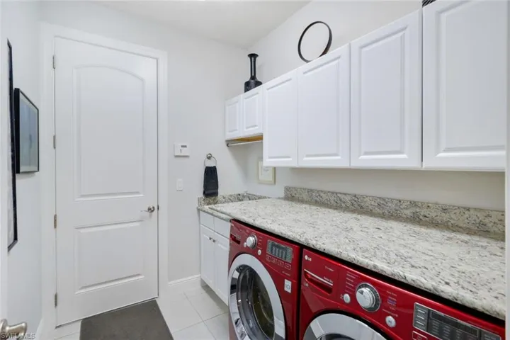 Clothes washing area featuring cabinets, washer and clothes dryer, and light tile patterned floors