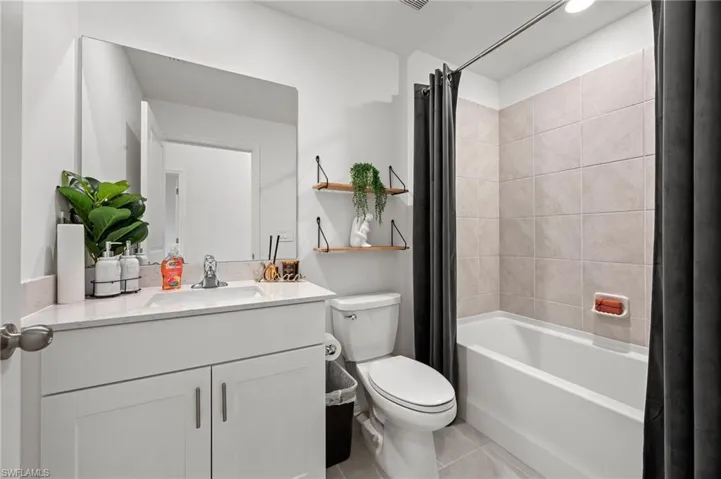 Full bath featuring shower / tub combo with curtain, vanity, and light tile patterned floors